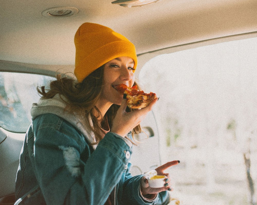 chica comiendo pizza en una furgoneta